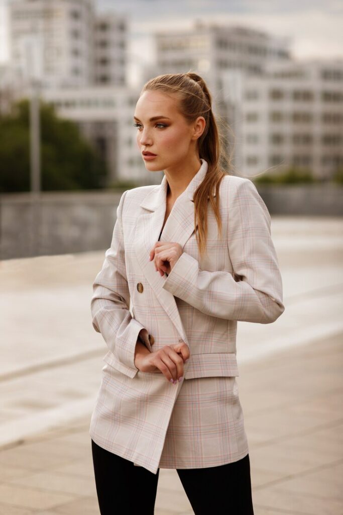 Showcasing the craft of luxury at Style Haven, a woman exudes elegance in a tailored beige plaid blazer and black trousers in an urban setting."